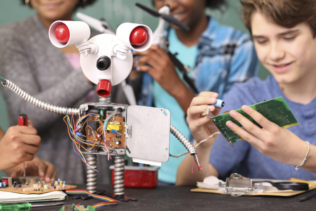 Schüler*innen arbeiten an einem Roboter.