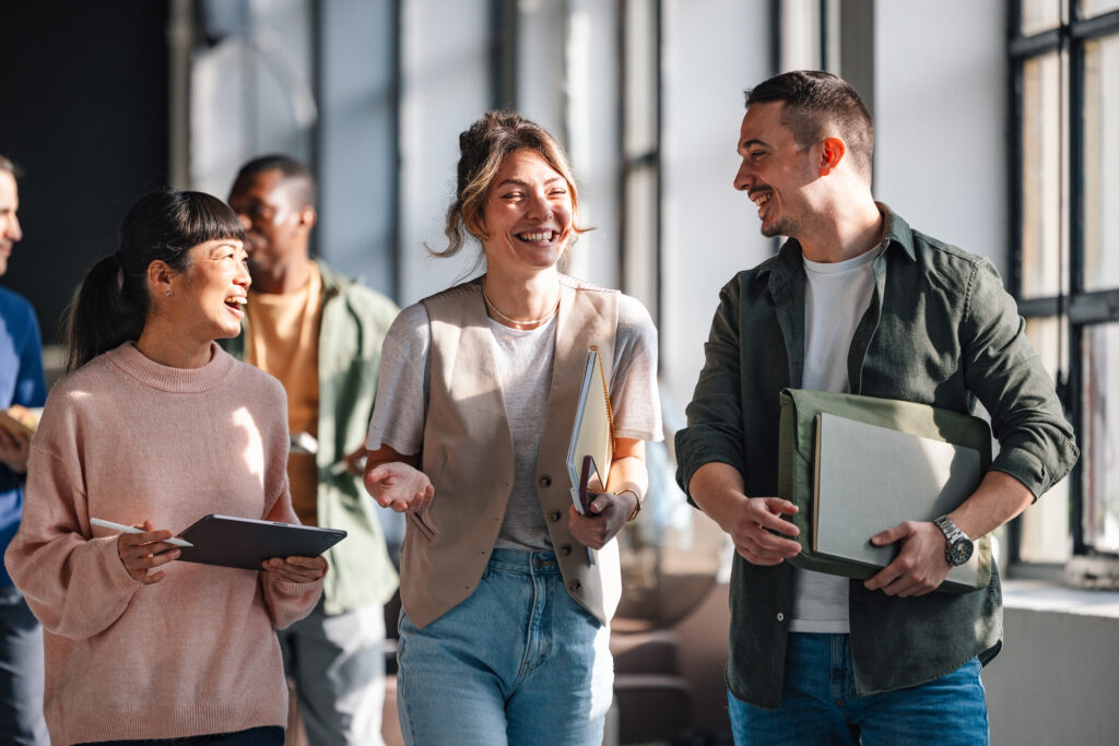 Eine Gruppe junger Erwachsener, unterhält sich während sie in einem Gebäude laufen.